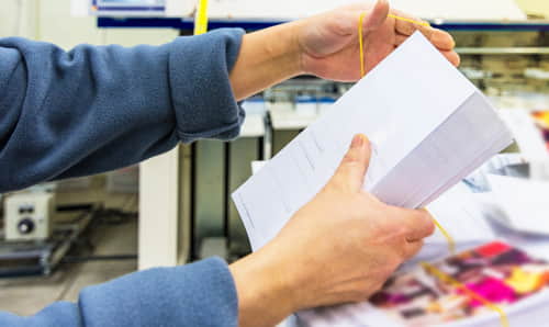 Mujer ordenando una resma de papel de imprenta, cartas sobres