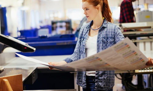 Mujer tomando un pliego de papel de imprenta reciclado. Papel recicaldo papel